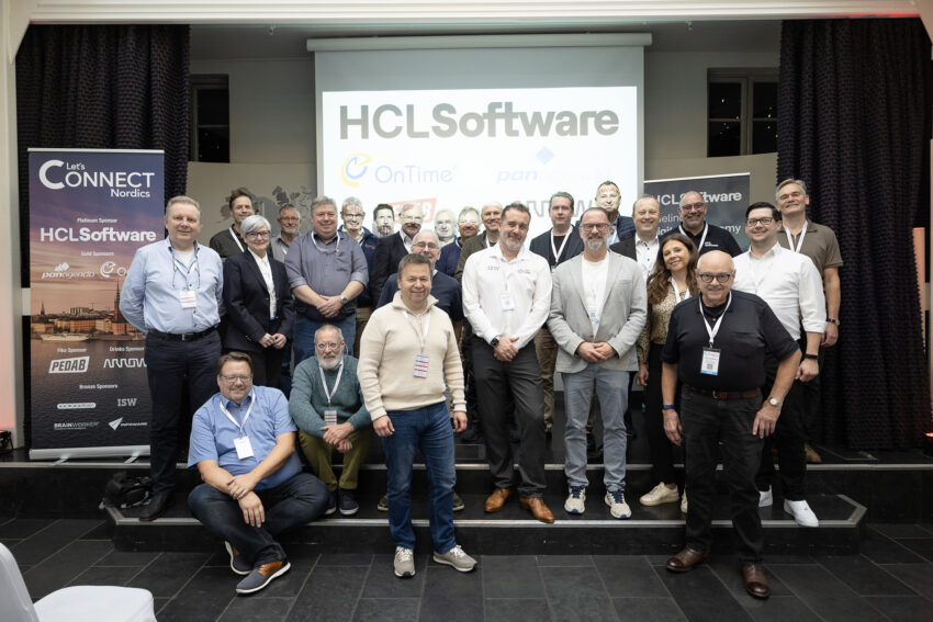 A group photo of people standing in front of a screen at a conference.